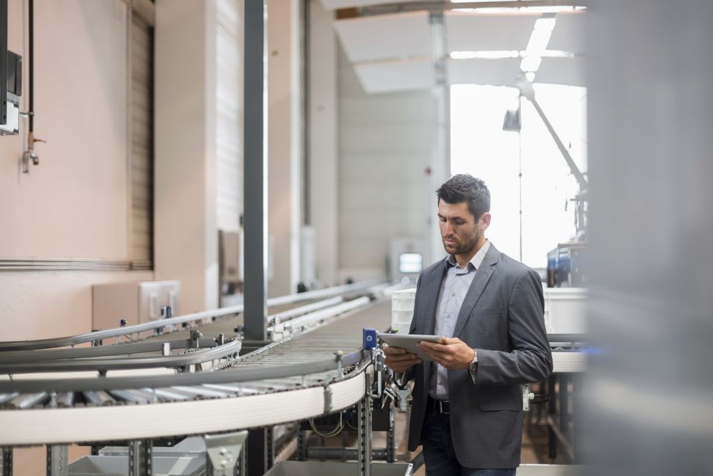 Businessman using tablet at conveyor belt in factory